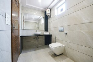A modern bathroom with a white sink, a toilet, and a large mirror. - Fabhotel Angel Green Residency (Gurugram)