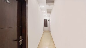 Un couloir étroit, avec une porte en bois portant le numéro « 108 » sur le côté gauche et une porte simple au fond.
