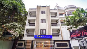 Un hôtel à plusieurs étages, doté d’une façade moderne, d’une enseigne « fabHOTELS » bien visible et d’une entrée sécurisée par un portail.