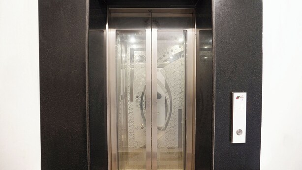 Un ascenseur doté d’une porte en verre et d’une poignée métallique.