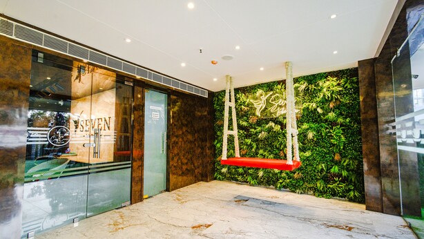 A lobby with a glass wall, a wooden reception desk, and a green wall with a climbing plant. - Fabhotel Prime Seven Lake View (Hyderabad)