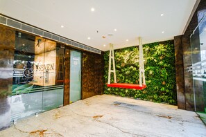 A lobby with a glass wall, a wooden reception desk, and a green wall with a climbing plant. - Fabhotel Prime Seven Lake View (Hyderabad)