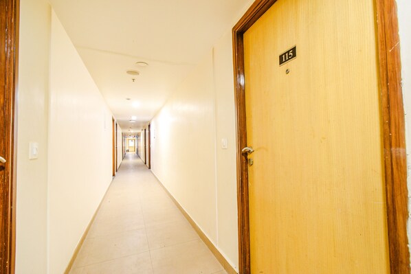 A long, narrow hotel corridor with wooden doors on either side, leading to a central hallway. - Fabhotel Prime Seven Lake View (Hyderabad)