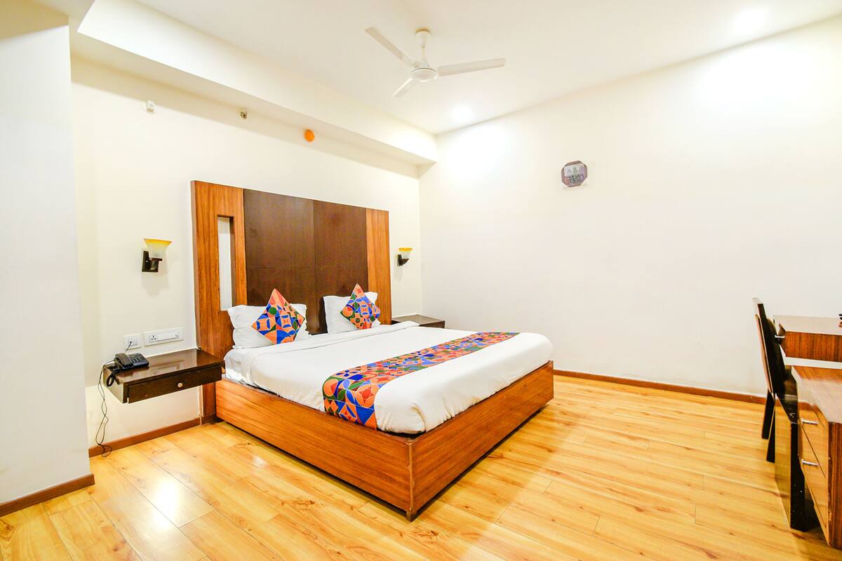 A modern hotel room with a wooden bed, a desk, and a chair.