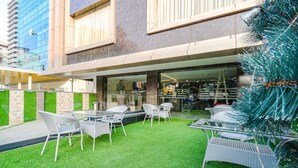 An outdoor patio with artificial grass, white wicker furniture, and a glass table. - Fabhotel Prime Seven Lake View (Hyderabad)