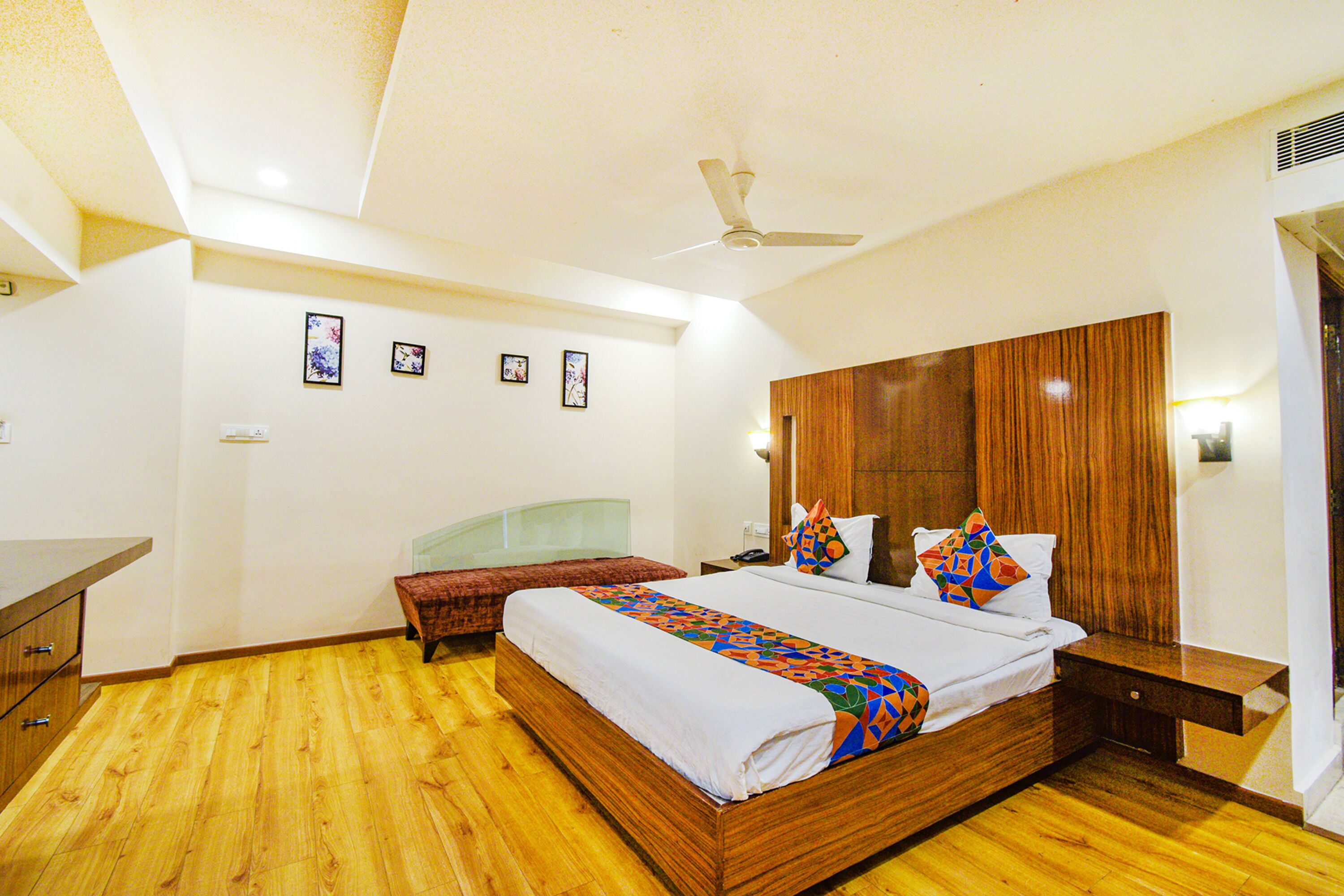 A bedroom with a wooden bed, a bench, a desk, and a ceiling fan.