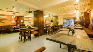 A restaurant with multiple dining tables and chairs, a bar area, and a seating section with cushioned benches. - Fabhotel Prime Seven Lake View (Hyderabad)