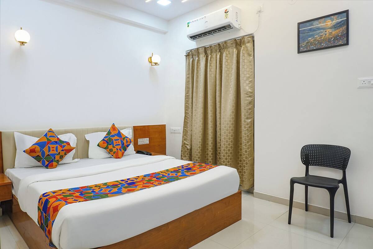 Une chambre d’hôtel avec un lit, une chaise, un climatiseur et un tableau au mur.