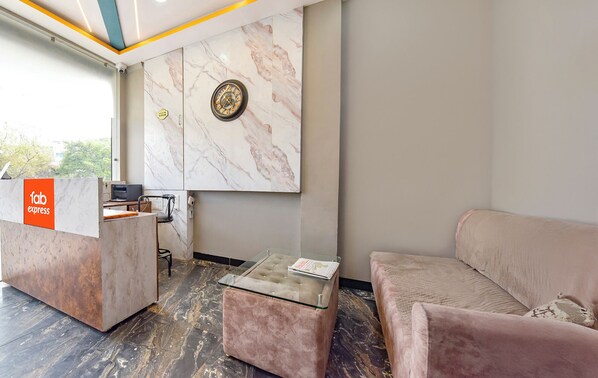 A reception area with a marble wall, a reception desk, a sofa, and a glass-top coffee table. - Fabexpress Lr (Ujjain)