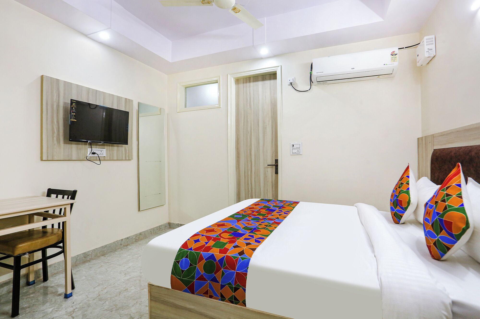 Une chambre d’hôtel équipée d’un lit, d’un bureau, d’une chaise, d’une télévision et d’un appareil de climatisation.