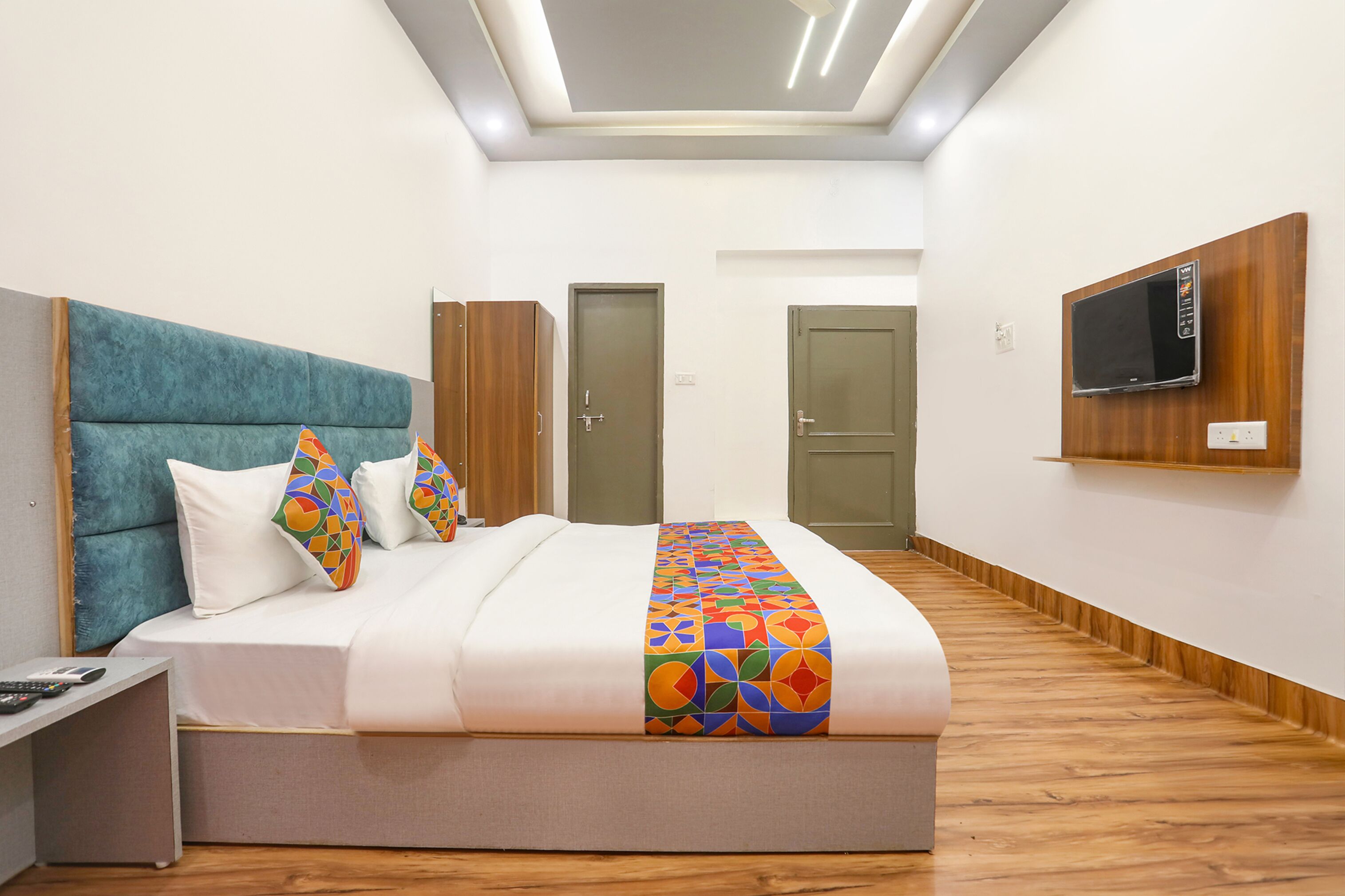 A modern hotel room with a large bed, a TV mounted on the wall, and a wooden floor.