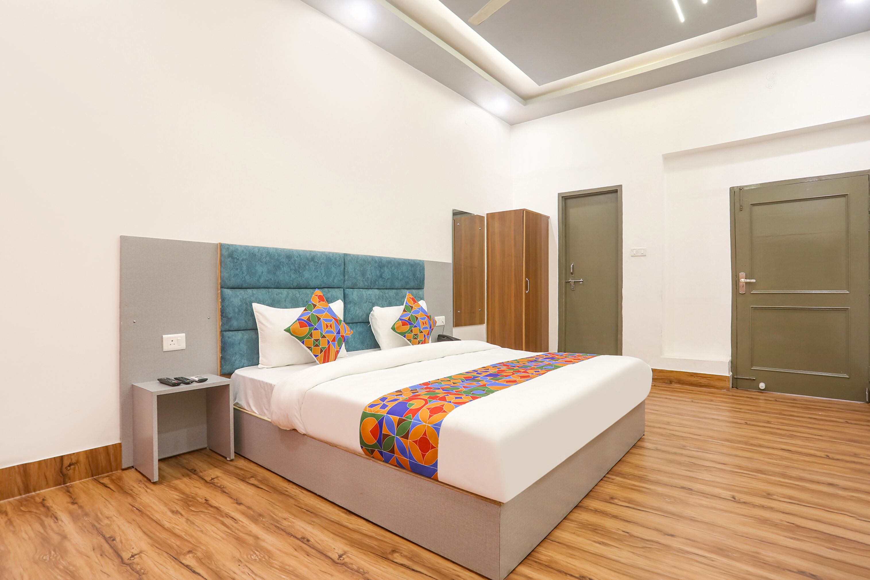 Une chambre moderne avec un grand lit, une table de chevet, une armoire et deux portes.