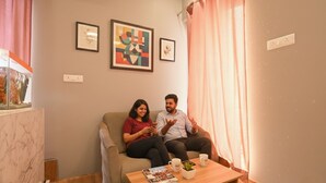 Un salón con sofá, una mesa de centro con revistas y una planta, y dos cuadros en la pared.