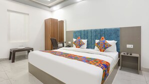 Una habitación de hotel con una cama grande, un armario de madera, un escritorio y una silla.