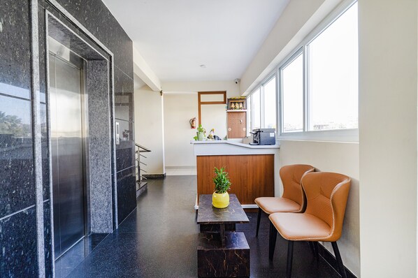 Un intérieur moderne comprenant un comptoir d’accueil, un espace détente et de grandes fenêtres offrant une vue dégagée.