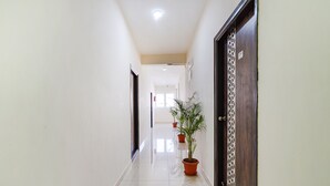 Un pasillo limpio y bien iluminado con una planta en maceta, una puerta con diseño decorativo y un cartel en la pared.