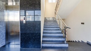 Un ascensor moderno y una escalera con barandillas y pasamanos de metal.