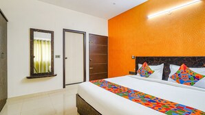 Habitación de hotel con cama, un espejo, un armario y una pared de acento naranja.