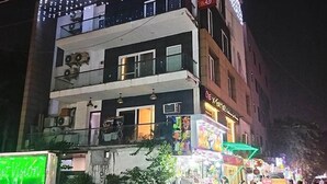 A multi-story building with balconies, a visible restaurant sign, and a brightly lit storefront below. - Fabhotel Casa De Grand (Prayagraj)
