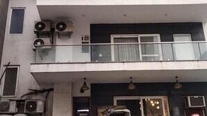 A multi-story building with air conditioning units, a balcony with a glass railing, and a door with a window. - Fabhotel Casa De Grand (Prayagraj)