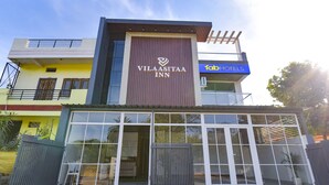 Um hotel com fachada moderna, grandes janelas de vidro e uma placa chamativa para Vilaasita Inn.