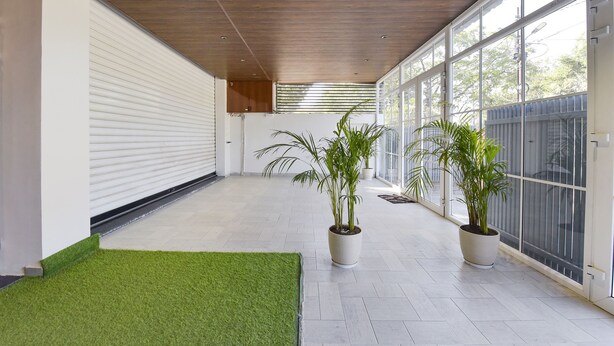 Um espaço interno amplo, com teto de madeira, grandes janelas e plantas em vasos.