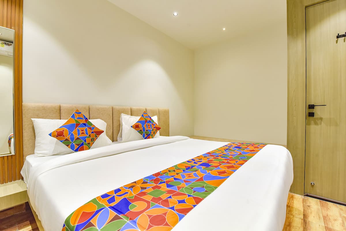 A hotel room with a large bed, a wooden headboard, and a wooden wardrobe.