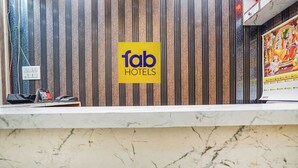 En receptionsdisk med et 'fab hotels' skilt, en kalender og en påfuglefjeder dekoration.