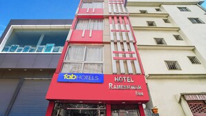 Et hotel med rød facade, et blåt skilt for Fab Hotels, og et skilt med navnet Rameshwar Inn.