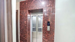 En elevator med væg af rød marmor og et digitalt display der viser tallet 3.