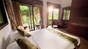Una habitación de hotel con una cama, un escritorio y vista al jardín.