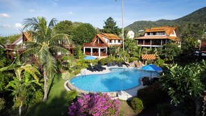 Un resort con piscina, palmeras y arquitectura tradicional.
