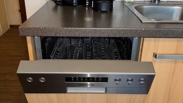 A kitchen with a dishwasher, a coffee maker, and a sink.
