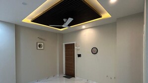 A spacious room with a polished marble floor, a ceiling fan, recessed lighting, and a door leading to another area. - Hotel Sky MMD (Jaipur)