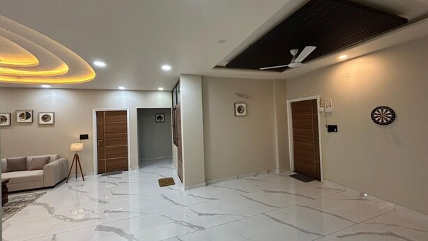 A spacious room with a marble floor, a sofa, a lamp, and a dartboard. - Hotel Sky MMD (Jaipur)