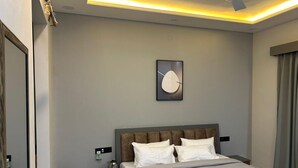 A modern hotel bedroom with a large bed, a nightstand with a lamp, and a wall-mounted artwork. - Hotel Sky MMD (Jaipur)