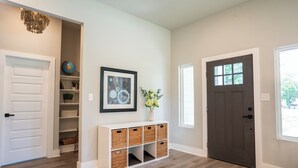 A hallway with a white door, a dark brown door, and a white console with wicker baskets.
