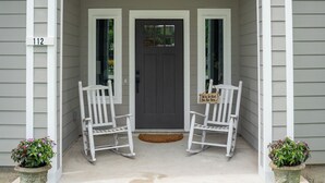 A house with a porch, two rocking chairs, and a door.
