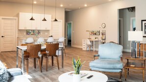 A modern living room with a dining area, kitchen, and a workspace.