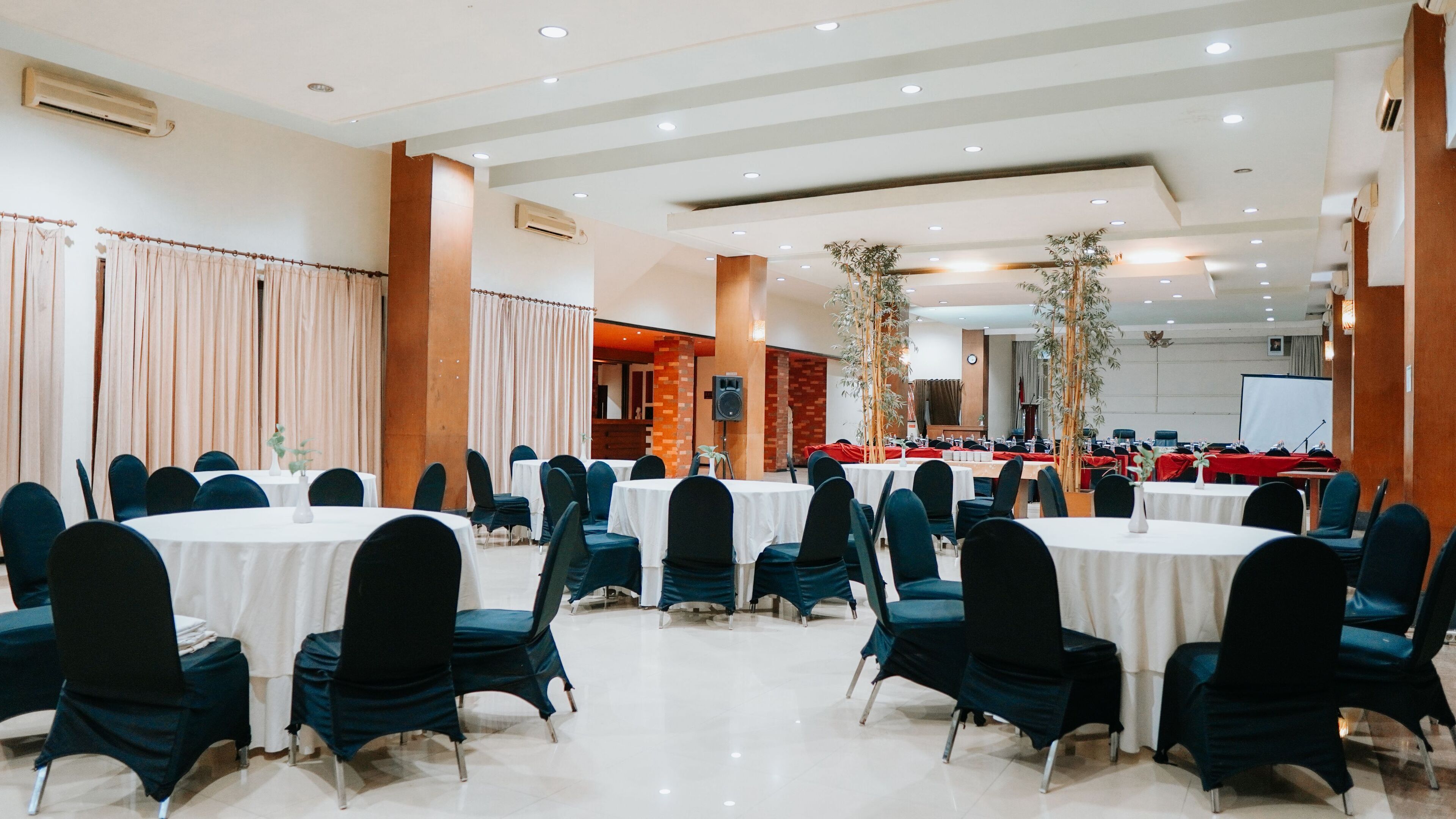 Uma sala de conferências com mesas redondas, cadeiras e um espaço para o palco.
