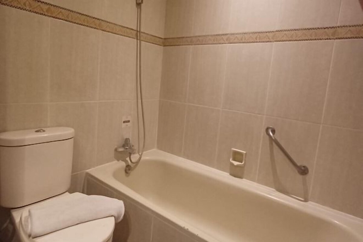 Un baño con una bañera blanca, un inodoro y un cabezal de ducha.