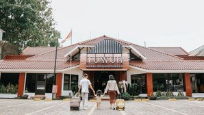 A hotel entrance with a tiled roof, a sign reading "TUYUH HOTEL AT KAYUTANGAN", and a flag on top. - Tuwuh Hotel at Kayutangan (Malang)