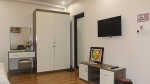 Ein Hotelzimmer mit Kleiderschrank, Schreibtisch mit Stuhl, Fernseher und einem Rauchverbotsschild.