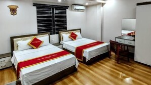 Ein Hotelzimmer mit zwei Betten, einem Schreibtisch, einem Stuhl und einer Klimaanlage.