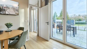 Et moderne interiør med et træspisebord, grønne stole, et stort vindue og udsigt til det fri.