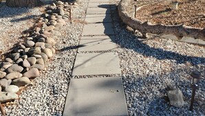 Un sentiero lastricato di ciottoli e rocce che conduce a una panchina di legno e a un tavolo da picnic.