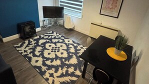 A living room with a patterned rug, a black table with a plant, a TV, and a fireplace. - 1br-2guests-freeparking-wifi-tv (Birmingham)