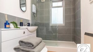 A modern bathroom with a white toilet, a glass shower enclosure, a white sink, and a mirror. - 1br-2guests-freeparking-wifi-tv (Birmingham)