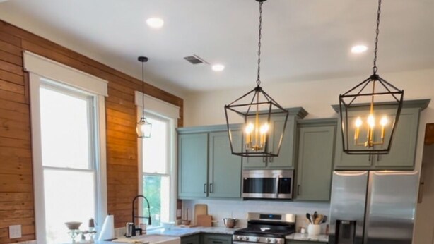 A modern kitchen with a central island, bar stools, and stainless steel appliances.