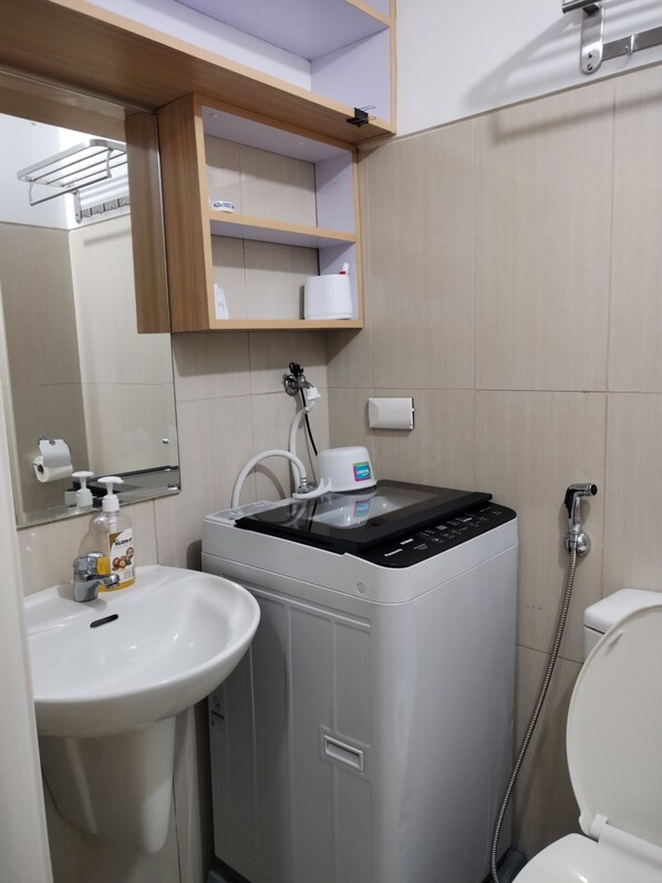 Un baño pequeño con lavamanos, un mueble bajo, inodoro y cabina de ducha.